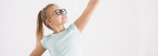 Portrait of a young girl with her arm and fist up and the other arm on a hip in a superhero pose on white wall background