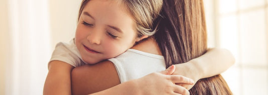 Beautiful young woman and her charming little daughter are hugging and smiling