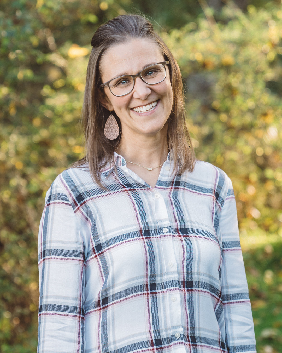 Author Jennifer Goebbel standing in a field smiling with the sun on her face